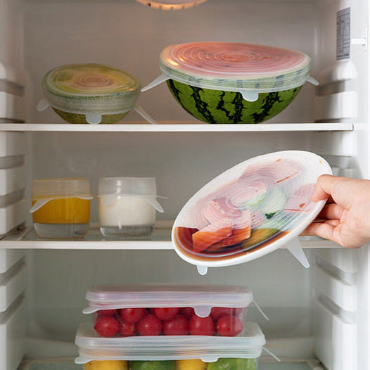 Hand opening a refrigerator door with a container of food inside.