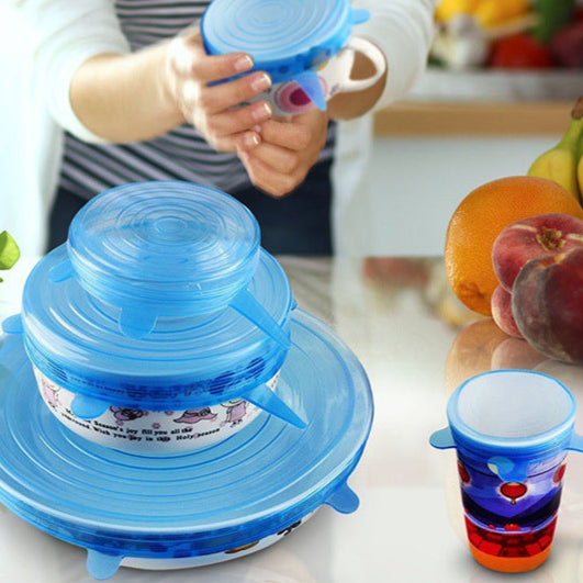 Blue silicone lid on a kitchen counter with colorful cups and fruits in the background