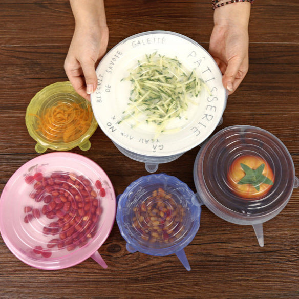 Colorful silicone lids on bowls with food on a wooden surface